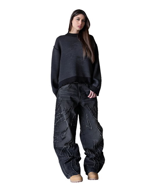 Woman wearing affordable streetwear baggy denim pants with a black sweater and tan shoes