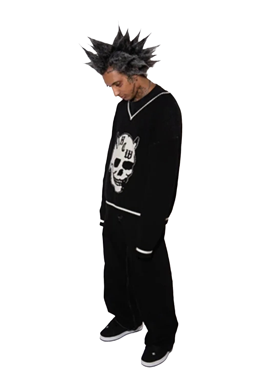 Man wearing baggy jeans with graphic design and black sweater featuring skull print on black background