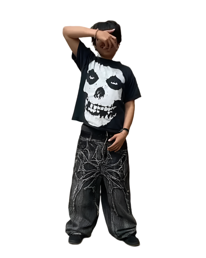 Person wearing black spider embroidered jeans with bold spider design and black graphic skull t-shirt