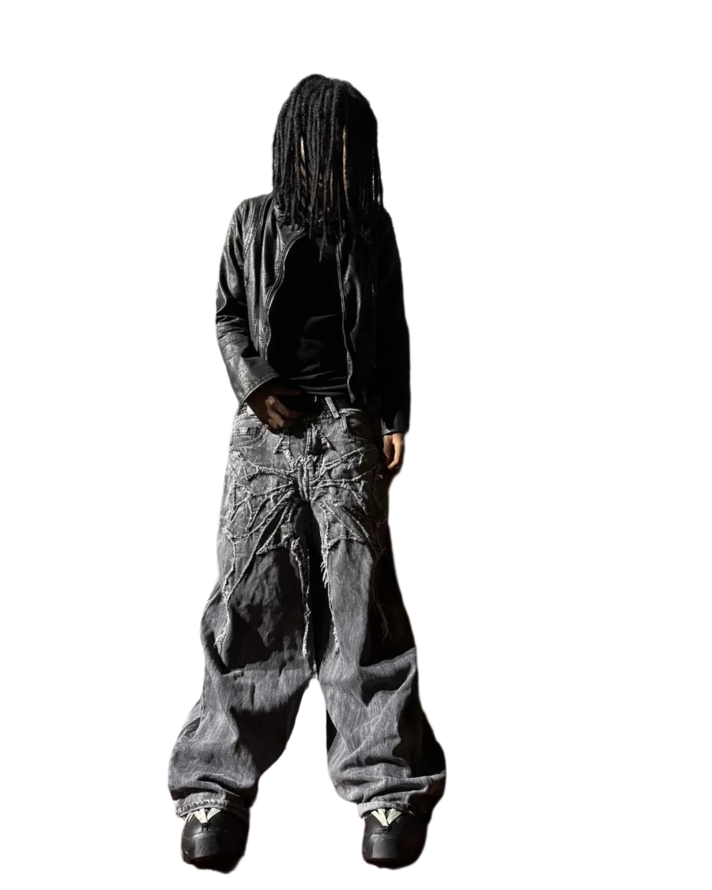 Person wearing spider embroidered jeans with black leather jacket and sneakers on black background